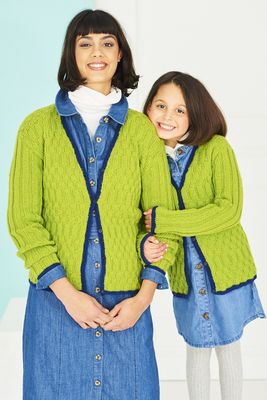A woman and a girl are wearing matching green knitted cardigans with navy blue trim.