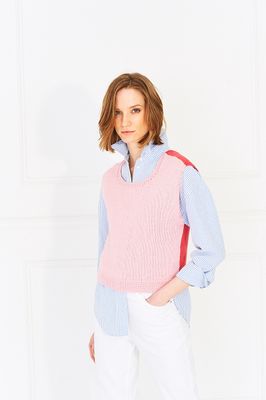 A woman is wearing a knitted top, the front in pink and the back in red.