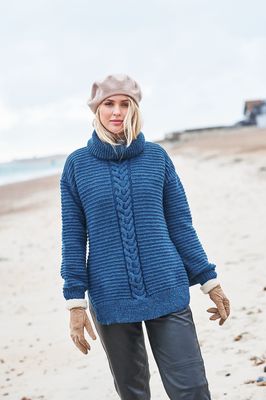 A woman is wearing a dark blue knitted sweater with a cable panel down the centre.
