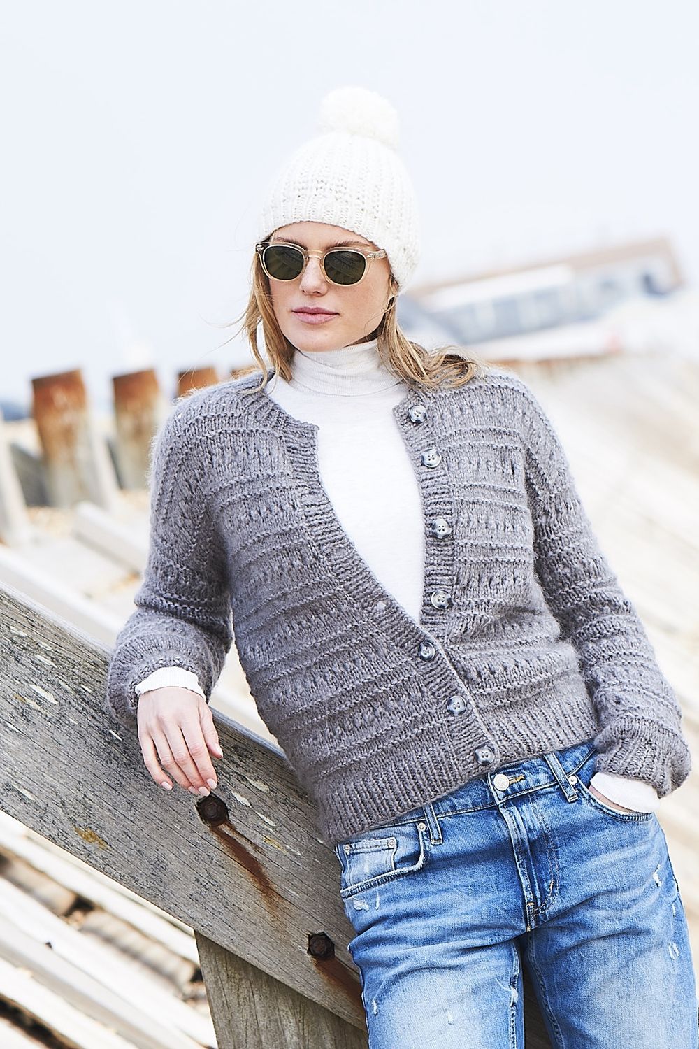 A woman is wearing a grey knitted cardigan.