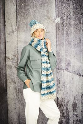 A woman is wearing a blue and cream knitted scarf and hat.