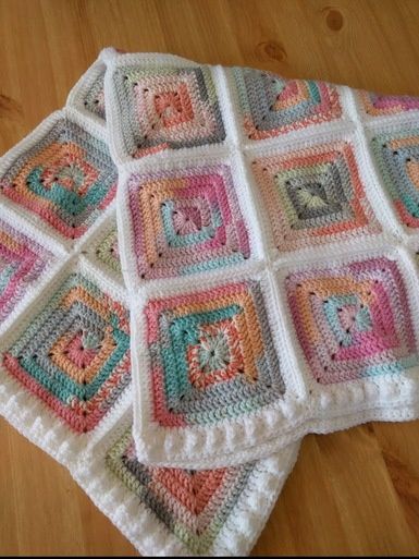 A crocheted blanket made up of multicoloured squares and joined in white.