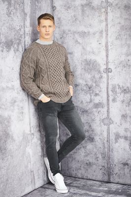 A man is wearing a taupe cable knit sweater.