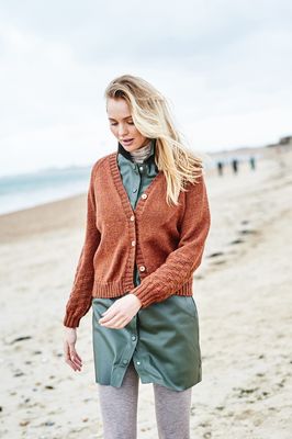 A woman is wearing a burnt orange knitted cardigan.