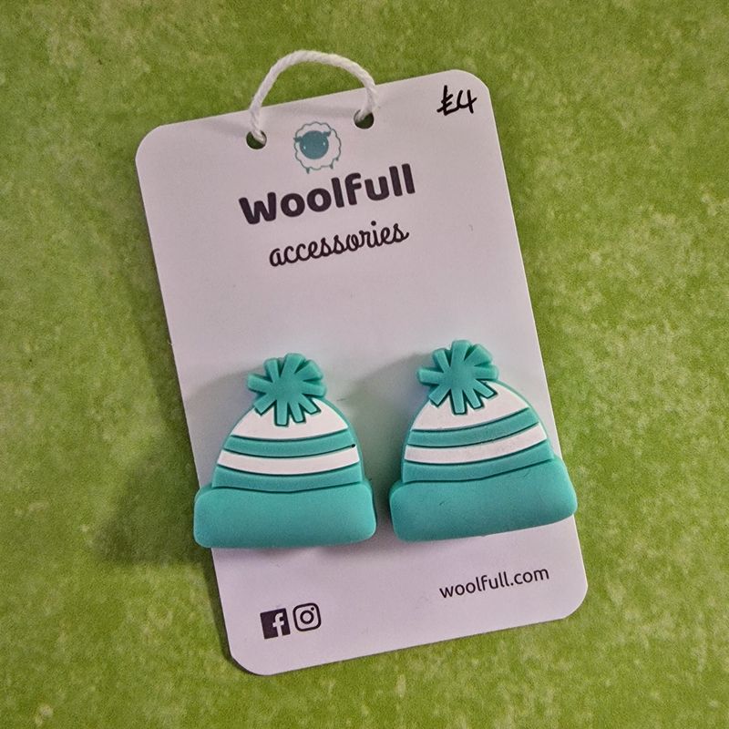 A green background with a pair of bobble hat shaped point protectors mounted on a white card.