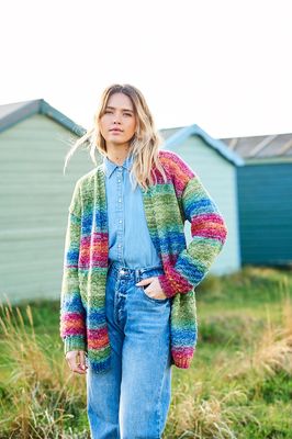 A woman is wearing a knitted cardigan in shades of red, blue and green.