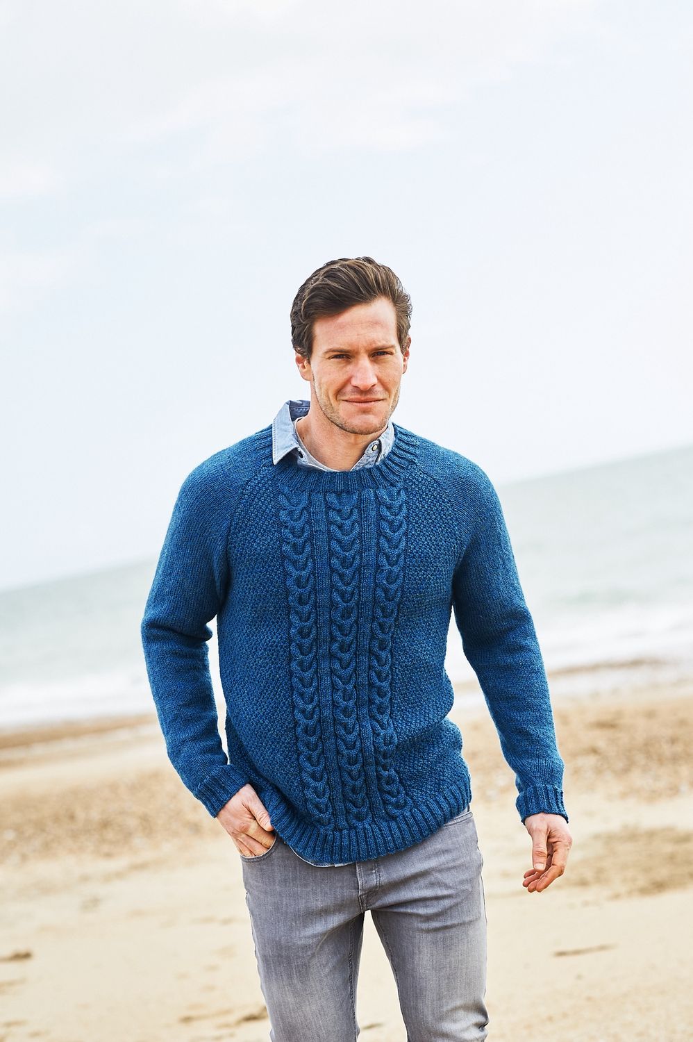A man is wearing a dark blue knitted sweater.