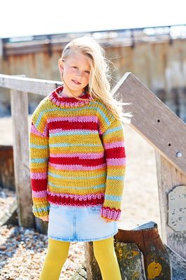 A girl is wearing a variegated knitted sweater in shades of blue, pink, red and green.