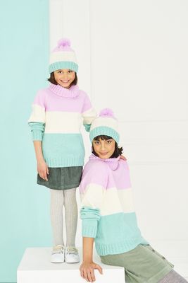 A woman and a girl are wearing matching knitted sweaters and hats in pink, cream and aqua blue stripes.