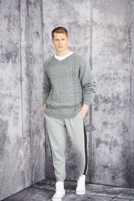 A man is wearing a grey knitted sweater with cable on the sides.