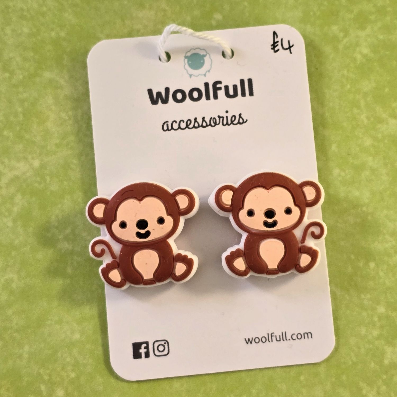 A green background with a pair of monkey shaped point protectors mounted on a white card.