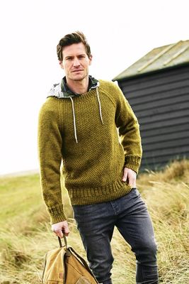 A man is wearing a green sweater with a moss stitch front.