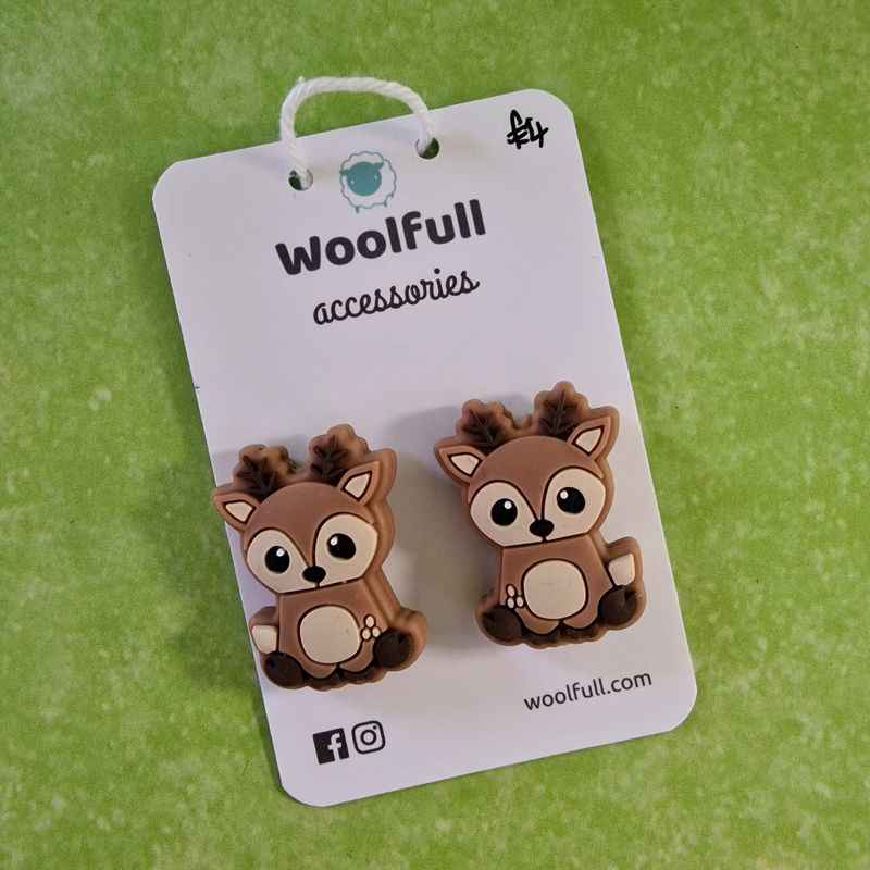 A green background with a pair of reindeer shaped point protectors mounted on a white card.