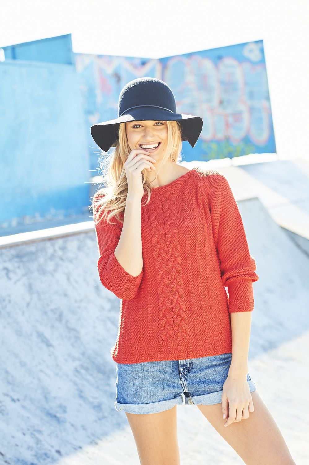 A woman is wearing a red cable knit sweater.