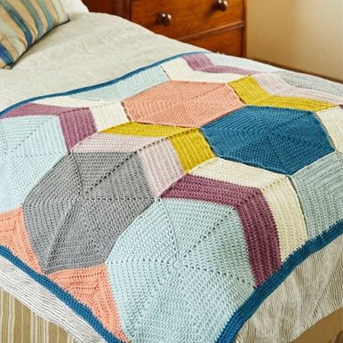 A crocheted blanket made up of hexagons in blue, purple, cream, yellow and peach.