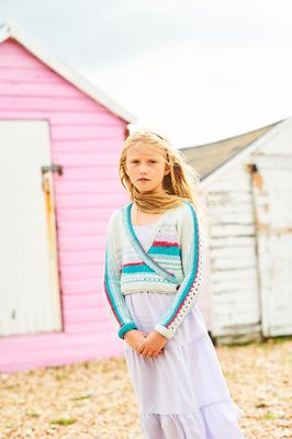 A girl is wearing a knitted ballet top in shades of cream, red, pink and blue.