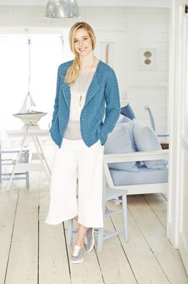 A woman is wearing a denim blue crocheted cardigan.