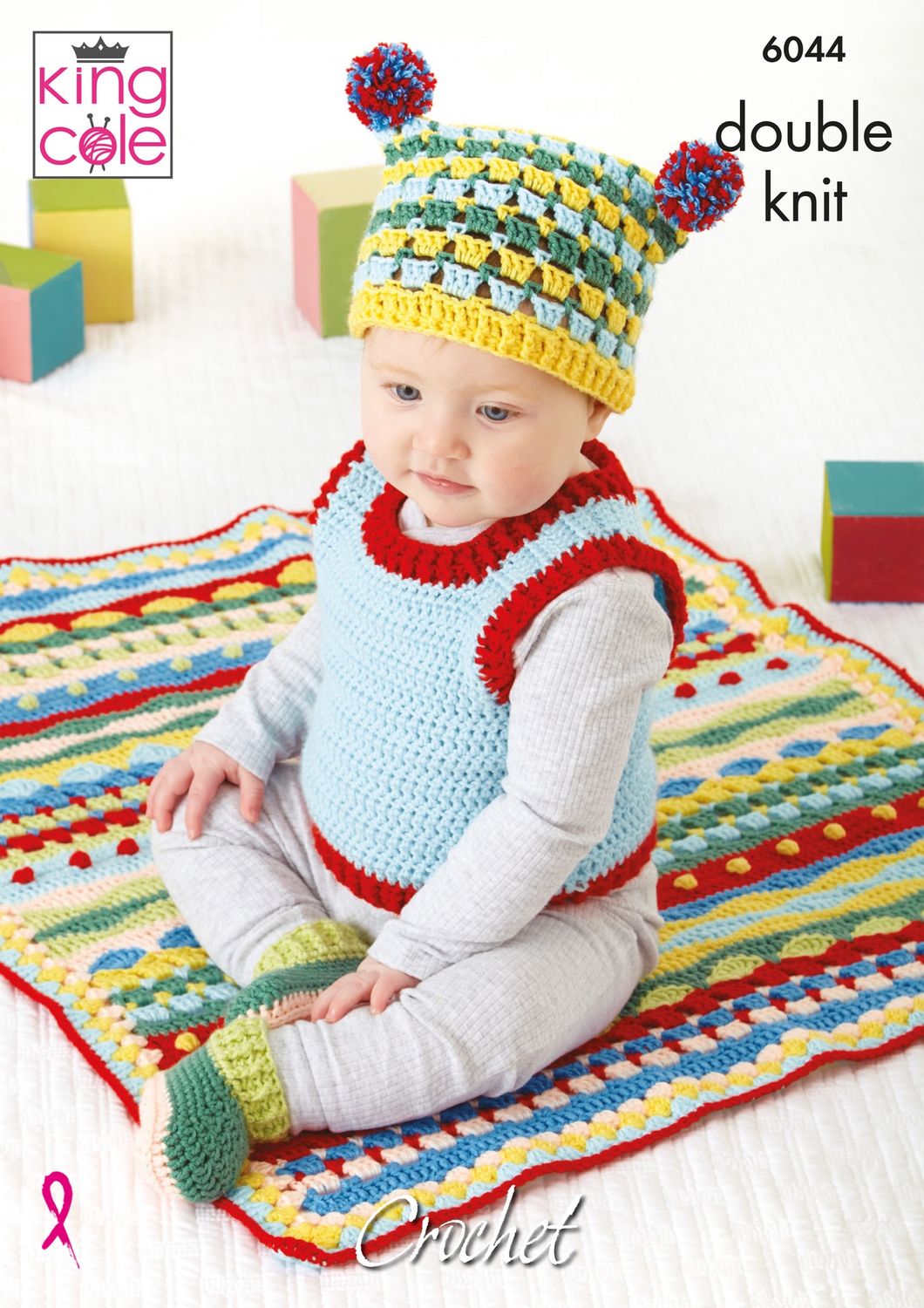 A baby is wearing a crocheted red and blue tank top, yellow, blue and green hat, green booties and sat on a red, blue yellow, green and beige blanket.