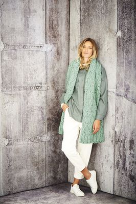 A woman is wearing a sage green knitted scarf.