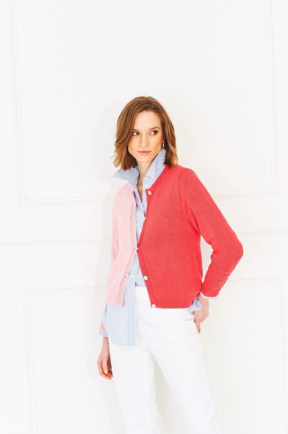 A woman is wearing a knitted cardigan, half in pink and half in red.