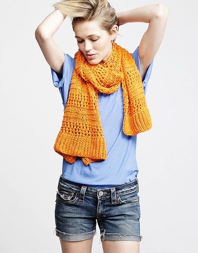 A woman is wearing an orange knitted scarf.