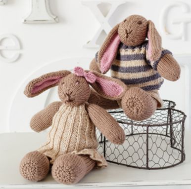 2 brown knitted rabbits wearing knitted clothes.