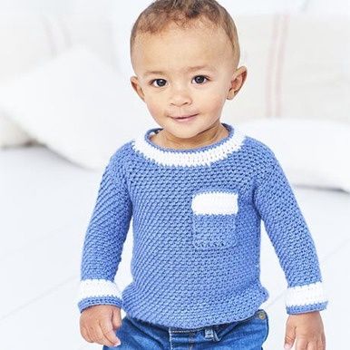 A baby is wearing a blue crocheted sweater with white edging.