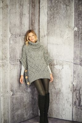 A woman is wearing a grey knitted poncho.