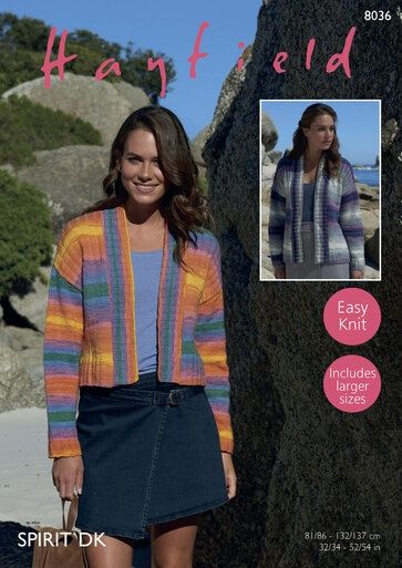 A woman is standing in front of rocks wearing a knitted cardigan in shades of orange, blue, purple and yellow.