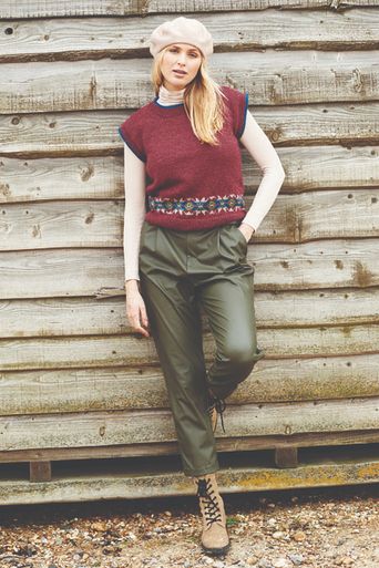 A woman is wearing a dark red knitted tank top with a small amount of fair isle around the bottom edge.