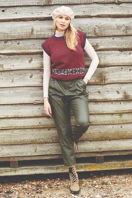 A woman is wearing a dark red knitted tank top with a small amount of fair isle around the bottom edge.