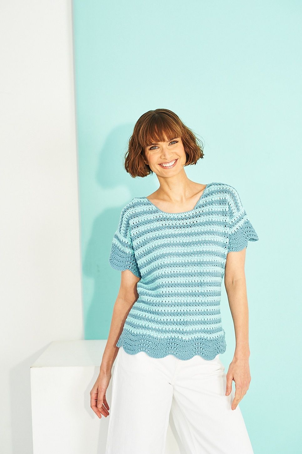 A woman is wearing a blue striped crocheted top.
