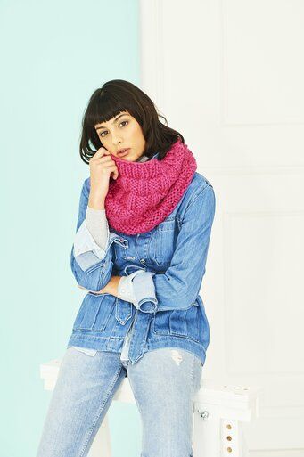 A woman is wearing a bright pink knitted cowl.
