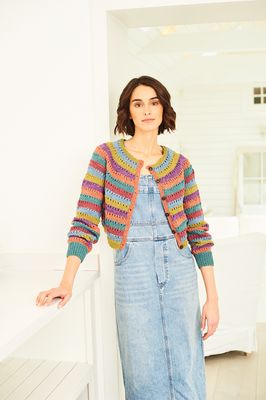 A woman is wearing a striped knitted cardigan in shades of green, blue, pink, purple, teal and orange.