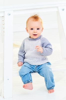 A baby is wearing a knitted sweater in light grey and mid grey.
