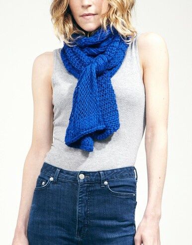 A woman is wearing a royal blue knitted scarf.