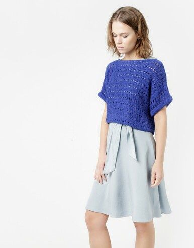 A woman is wearing a royal blue knitted short sleeved sweater.
