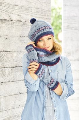 A woman is wearing a knitted hat, cowl and wristwarmers, all in light blue with small amounts of pink and dark blue colourwork.