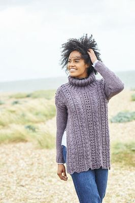 A woman is wearing a purple lacy knitted tunic.