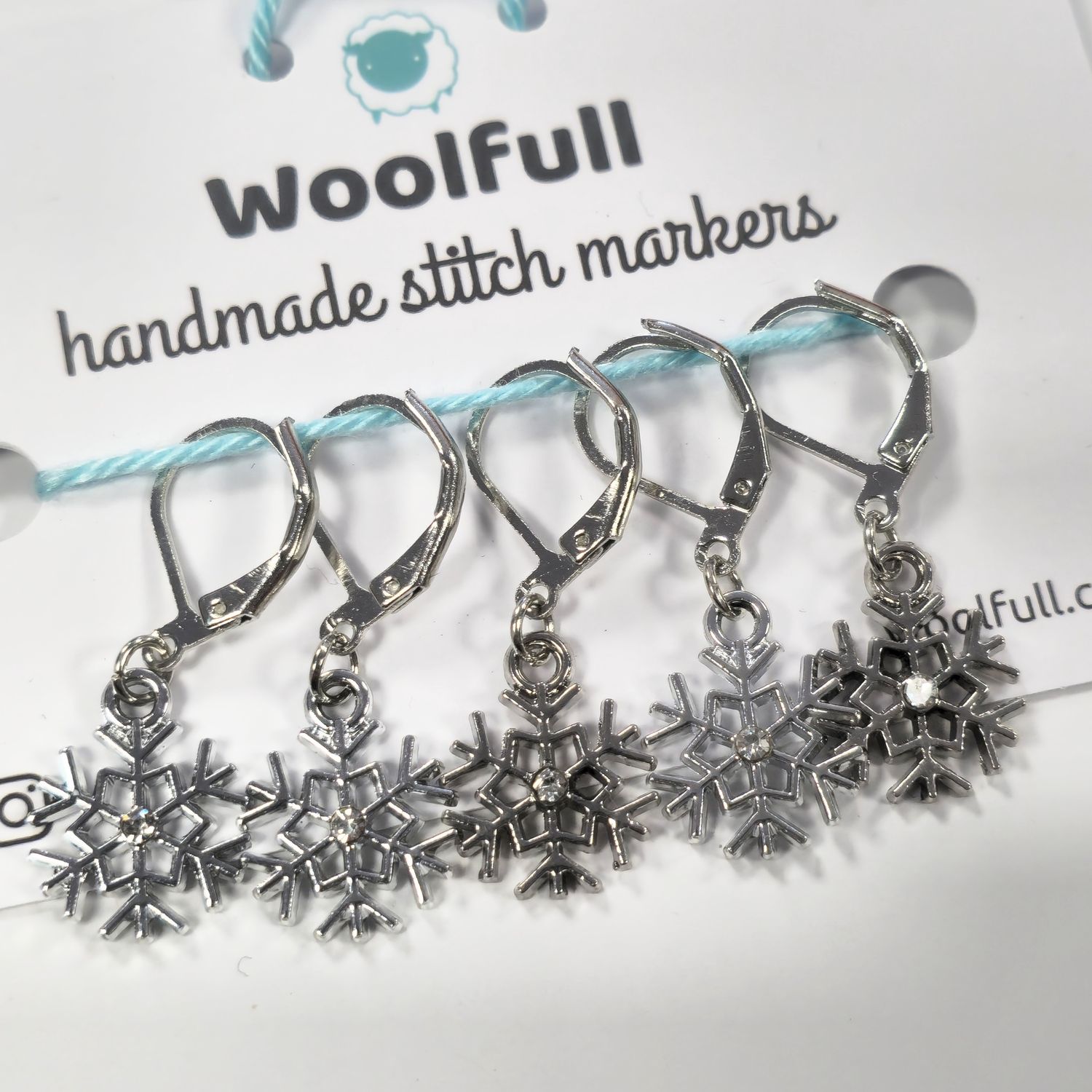 5 shiny silver snowflake shaped stitch markers.