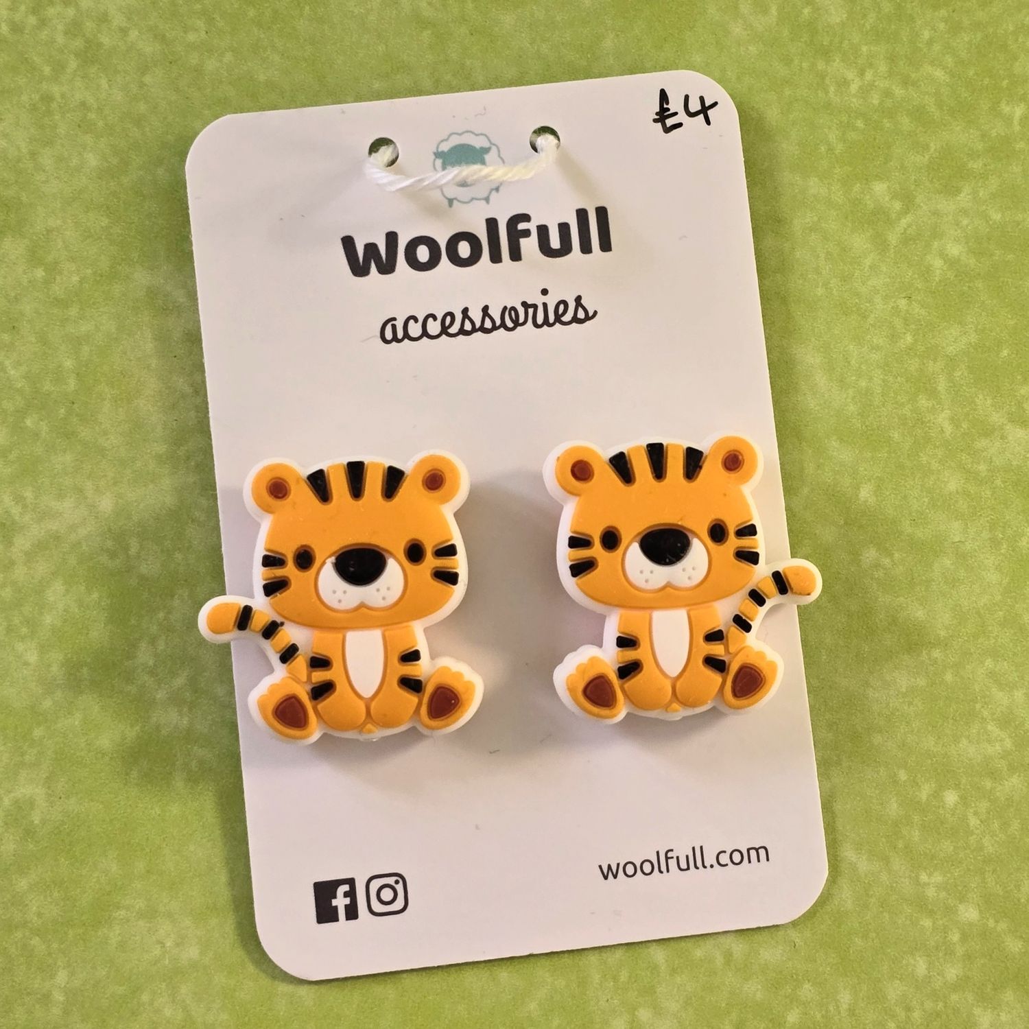 A green background with a pair of tiger shaped point protectors mounted on a white card.