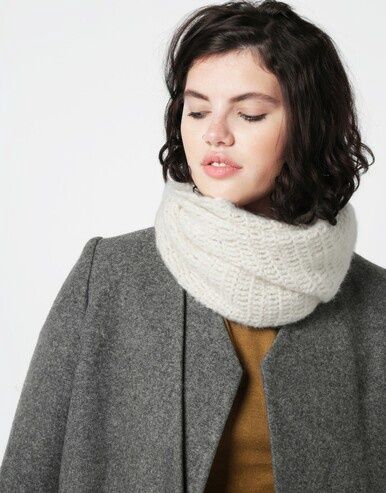 A woman is wearing a cream crocheted cowl.