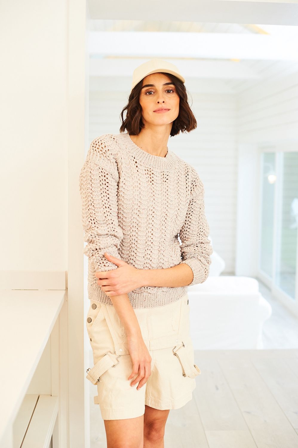 A woman is wearing knitted sweater in cream.