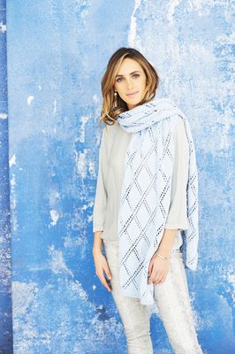 A woman is wearing a very pale blue knitted shawl with a diamond lace pattern.