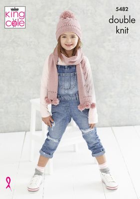 A girl is wearing a pink knitted hat and scarf with lace heart detail and pompoms.