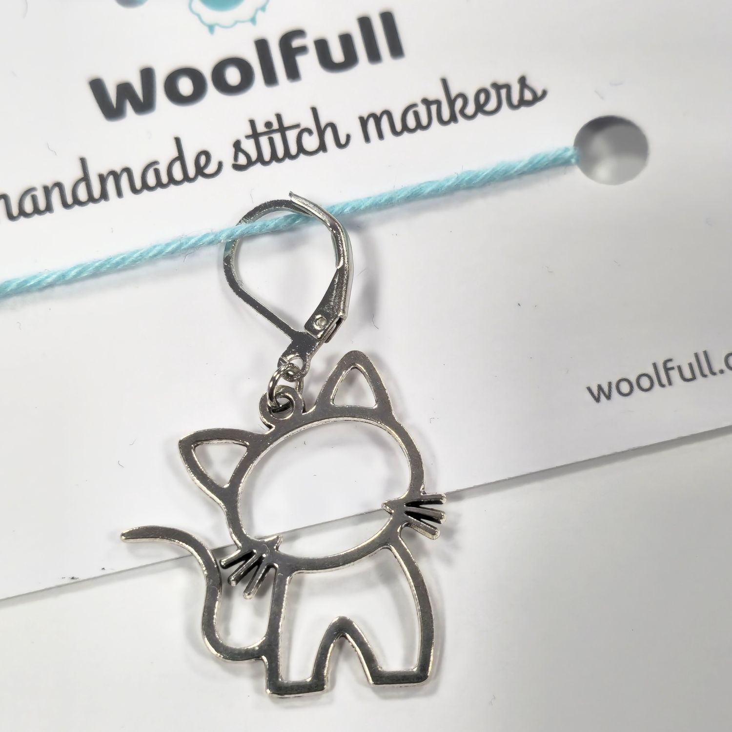 A silver metal cat shaped stitch marker.
