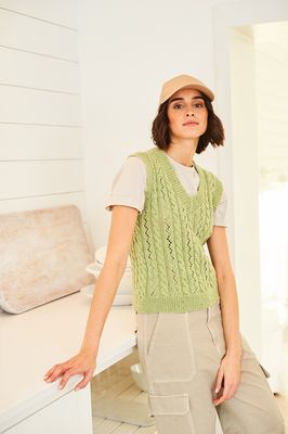 A woman is wearing a v neck knitted tank top in light green.