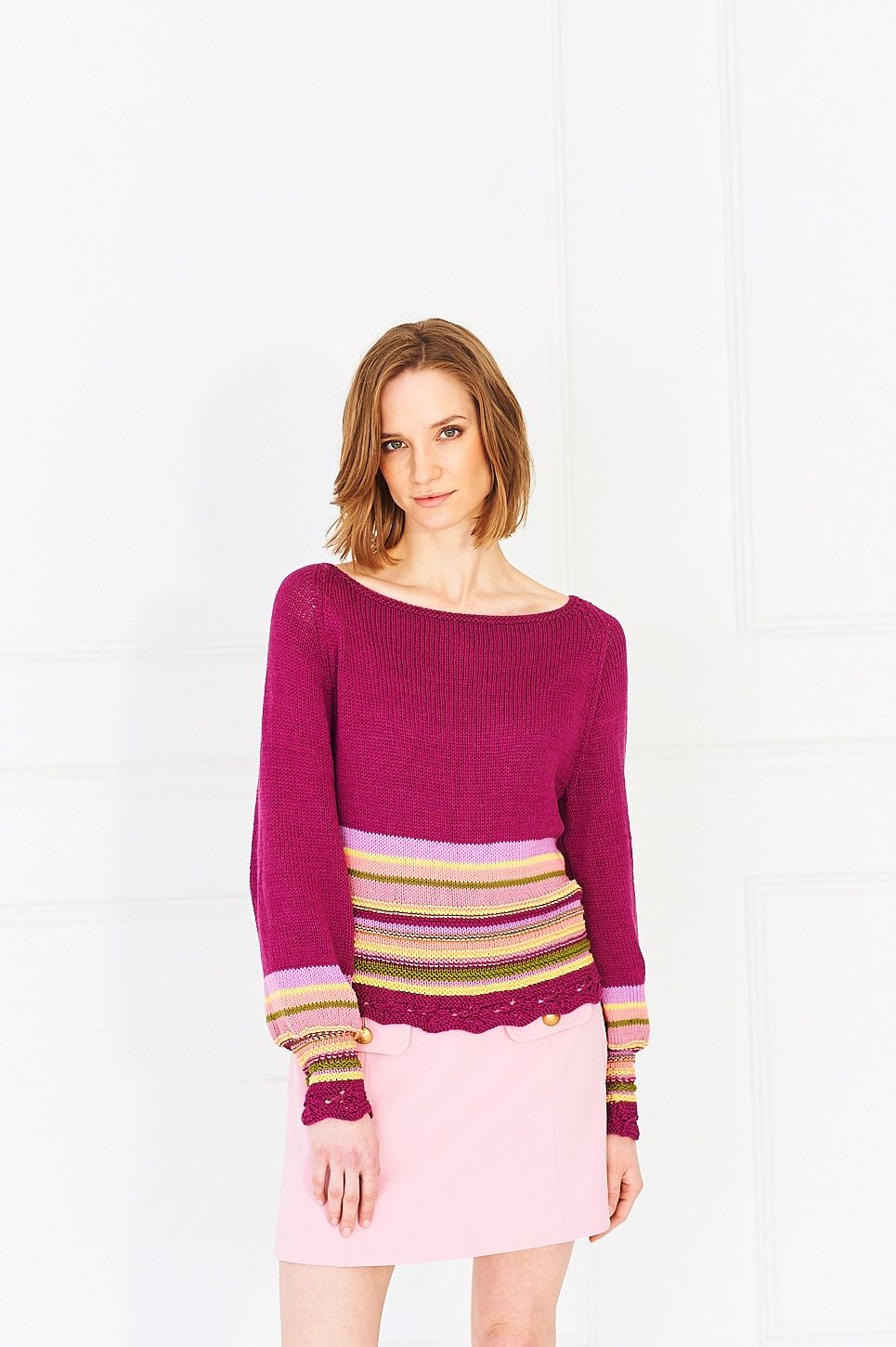 A woman is wearing a knitted sweater in purple, pink, yellow and green.