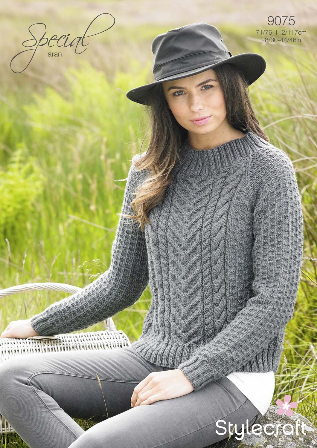 A woman is wearing a grey cable knit sweater.