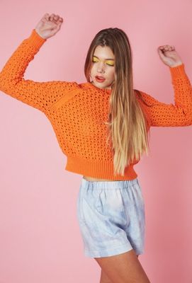 A woman is wearing a bright orange knitted sweater.